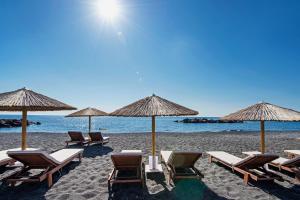 a group of chairs and umbrellas on a beach at Nissia Beach Apartments & Suites in Kamari