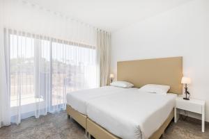 a bedroom with a large bed and a large window at Algarve Race Resort - Apartments in Portimão