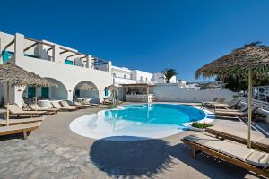 a pool with chaise lounge chairs and a resort at Nissia Beach Apartments & Suites in Kamari