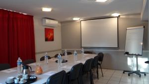 a meeting room with a long table with chairs and a screen at HOTEL RESTAURANT OLYMPE in Aix-en-Provence