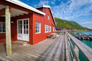 a red building on a dock with boats in the water at Lofoten Seaview Villa in Leknes