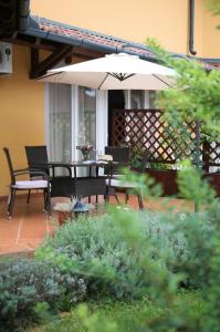 a patio with a table and chairs and an umbrella at Villa Toscana in Hajdúszoboszló