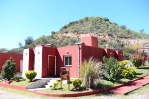 una casa roja con una montaña en el fondo en Complejo Los Paraísos, en Potrero de los Funes