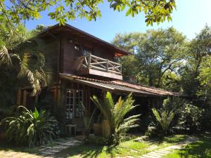 a wooden house with a balcony on top of it at Regina Guest House in Praia do Rosa