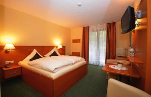 ein Hotelzimmer mit einem Bett und einem Flachbild-TV in der Unterkunft Hotel Burgfrieden in Beilstein