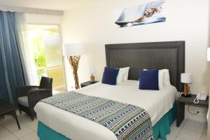 a bedroom with a large bed with blue pillows at Hotel Fleur d'Epee in Le Gosier