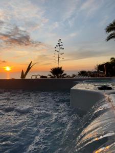 una piscina con puesta de sol en el fondo en ZenRepublic, your private villa with outdoor jacuzzi & pool with stunning ocean views, en Puntillo del Sol