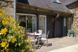 une terrasse en bois avec une table et des chaises sur une maison dans l'établissement Le Colombier Bretagne, à Louannec
