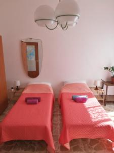 two beds with red covers in a room with a mirror at At Claudio and Inna's Home in Catania