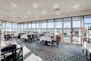 a dining room with tables and chairs and windows at Hotel Pinenhus in Glyngøre