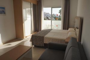1 dormitorio con cama, sofá y ventana en Apartamentos El Sombrero, en Acantilado de los Gigantes