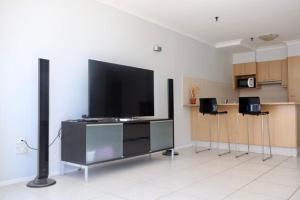 a living room with a flat screen tv and two stools at Focus OCEAN VIEW in Gold Coast