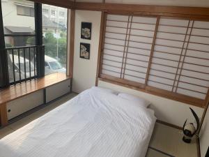 1 dormitorio con cama y ventana en ガナダン中央駅 2f 無料駐車場, en Kagoshima