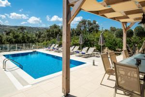 a swimming pool on a patio with a table and chairs at Villa Kalli Crete in Adelianos Kampos