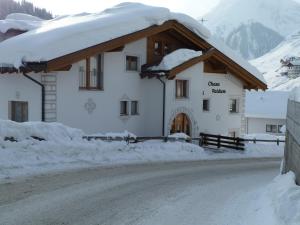 萨姆瑙恩Chasa Vaidum by MEIN SAMNAUN - MOUNTAIN HOMES的雪铺在雪铺上的道路上被雪覆盖的建筑物