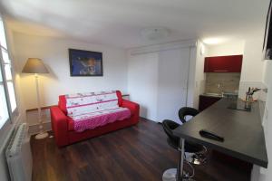 ein Wohnzimmer mit einem roten Sofa und einem Tisch in der Unterkunft Chambre chez l'habitant Le Rouge-Gorge - Cœur de Riquewihr - 2 personnes in Riquewihr