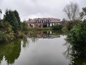 ein Haus an einem Fluss mit Häusern im Hintergrund in der Unterkunft Zajazd Rosa in Stoczek Łukowski