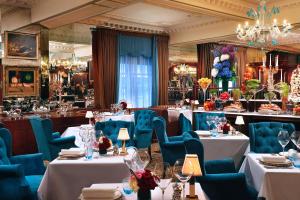 a restaurant with white tables and blue chairs at Rubens At The Palace in London