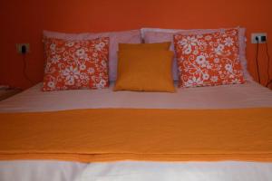 Una cama con almohadas naranjas y blancas. en LA CASA DI MAMMA 'NTO, en Castrofilippo