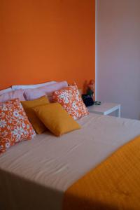 Una cama con paredes de color naranja y almohadas. en LA CASA DI MAMMA 'NTO, en Castrofilippo