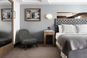 
a bedroom with a bed, desk, chair and mirror at Kimpton - Blythswood Square Hotel, an IHG Hotel in Glasgow
