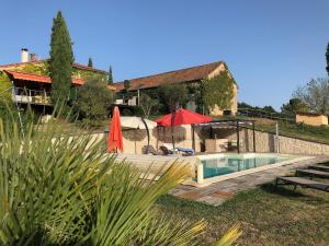 a house with a swimming pool and a red umbrella at Chambres à la Ferme de Pouzatel proche Bonaguil in Fumel