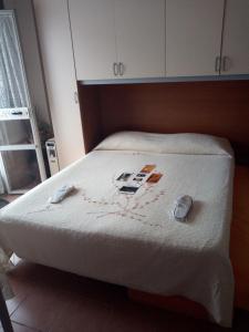um quarto com uma cama com lençóis brancos e sapatos em SoleLuna B&B em Cropani