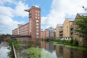 a building with a tower next to a river at I Should Cocoa (York) - Seebohm in York