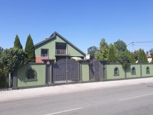 a green house with a fence on the side of a road at Apartments Delić in Nikšić