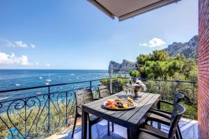 a table with a plate of food on a balcony overlooking the ocean at RELAIS TRITONE in Nerano