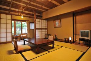 a living room with a wooden table and a television at Shibu Onsen KOKUYA in Yamanouchi