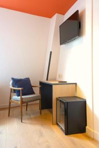 Habitación con silla, escritorio y TV. en Sparks Hostel en Róterdam