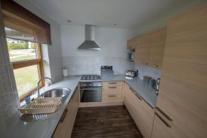 a kitchen with a sink and a stove at Loch Lomond Waterfront Luxury Lodges in Balmaha