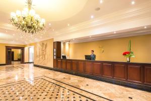 a man standing at the reception desk of a hotel lobby at Apartamentos Dann in Bogotá