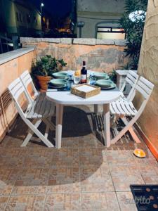 ゴルフォ・アランチにあるLa Terrazza sul Golfoの白いテーブル(椅子付)、ワイン1本