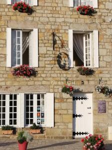 a stone building with white windows and flowers on it at Domfront - Numero CINQ in Domfront