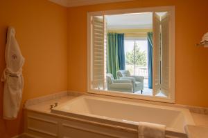 a bathroom with a tub and a mirror and a chair at The Yeatman in Vila Nova de Gaia