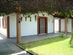 een wit huis met een deur en een grasveld bij Casa arejada e espaçosa in Bertioga