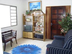 een woonkamer met een bank en een televisie bij Casa arejada e espaçosa in Bertioga