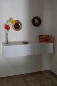 Un estante blanco con flores en un jarrón. en LA CASA DI MAMMA 'NTO, en Castrofilippo