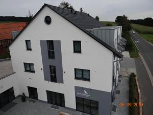 a white building with a black roof and a road at Apartmenthaus Vogel in Neuhof