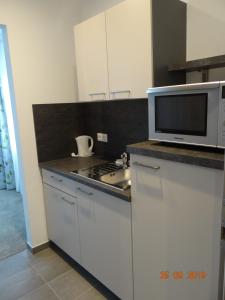 een witte keuken met een magnetron en een fornuis bij Apartmenthaus Vogel in Neuhof