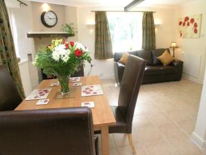 a living room with a table with a vase of flowers at The Shakespeare Lodge - Sleeps up to 12 - HOT TUB in Stratford-upon-Avon