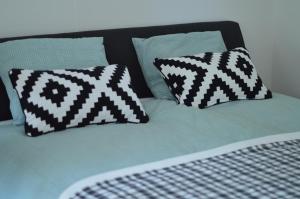 a bed with black and white pillows on it at Cosy Casa in Egmond aan Zee