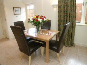 a dining room table with a vase of flowers on it at Juliet Cottage HOT TUB Sleeps 3 Singles or Double in Stratford-upon-Avon