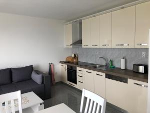 a kitchen with white cabinets and a couch at Apartments Diana in Šmrika