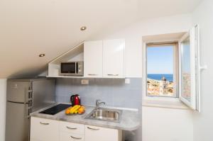 une cuisine blanche avec un évier et une fenêtre dans l'établissement Sea View Studio Positive Place - II, à Dubrovnik