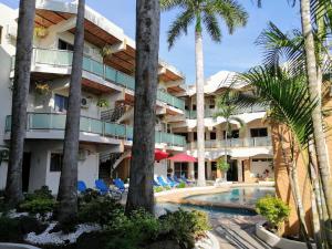 un complejo con piscina y palmeras en Hotel & Suites Mar y Sol Las Palmas, en Rincón de Guayabitos