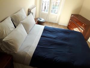 Una cama con sábanas y almohadas azules y blancas en un dormitorio en Apartamento céntrico catedral Burgos, en Burgos