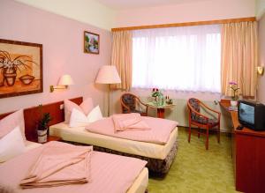 a hotel room with two beds and a television at Hotel Stadt Wittstock in Wittstock